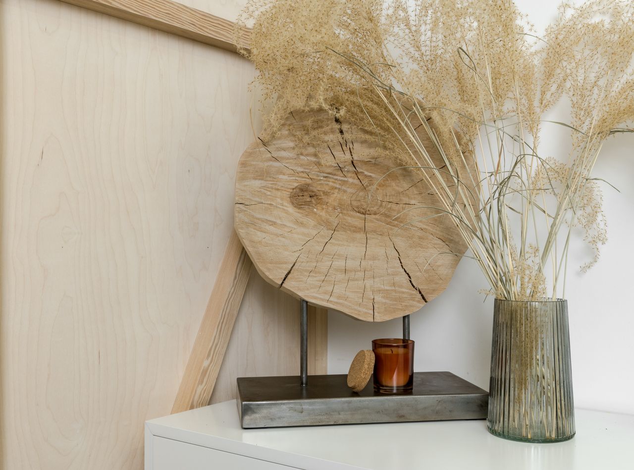 why-choose-us A stylish interior decor setting featuring dried plants in a glass vase and wooden accents.